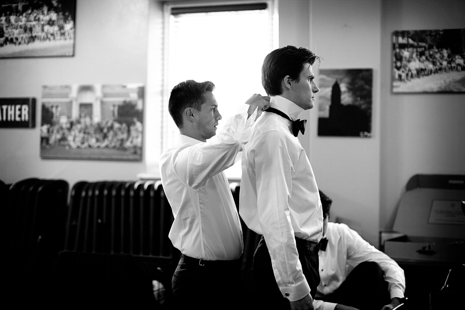 Black and white image of groomsmen getting ready in formal attire.