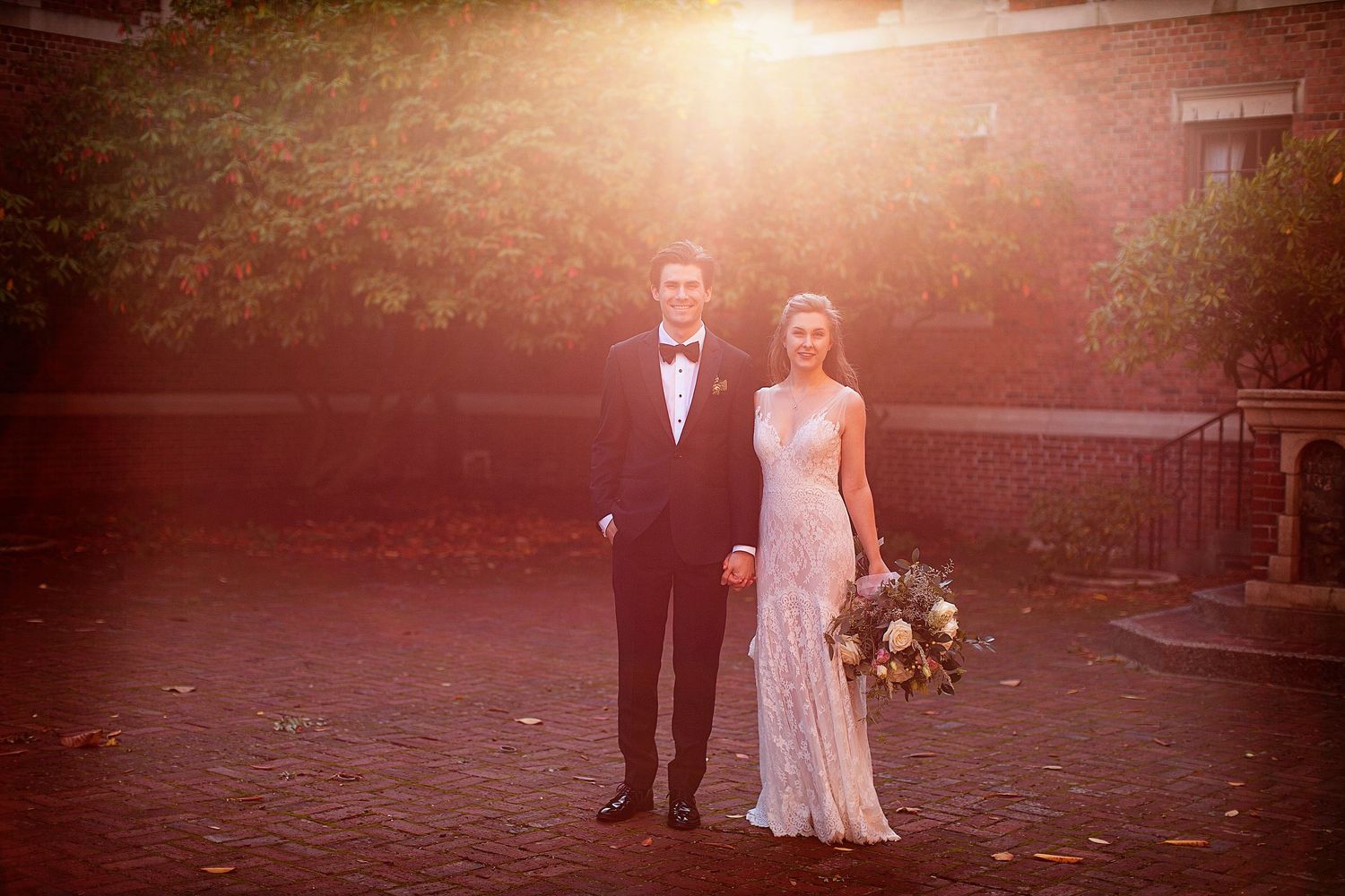 Romantic sunset silhouettes of a wedding couple against warm glowing sky.