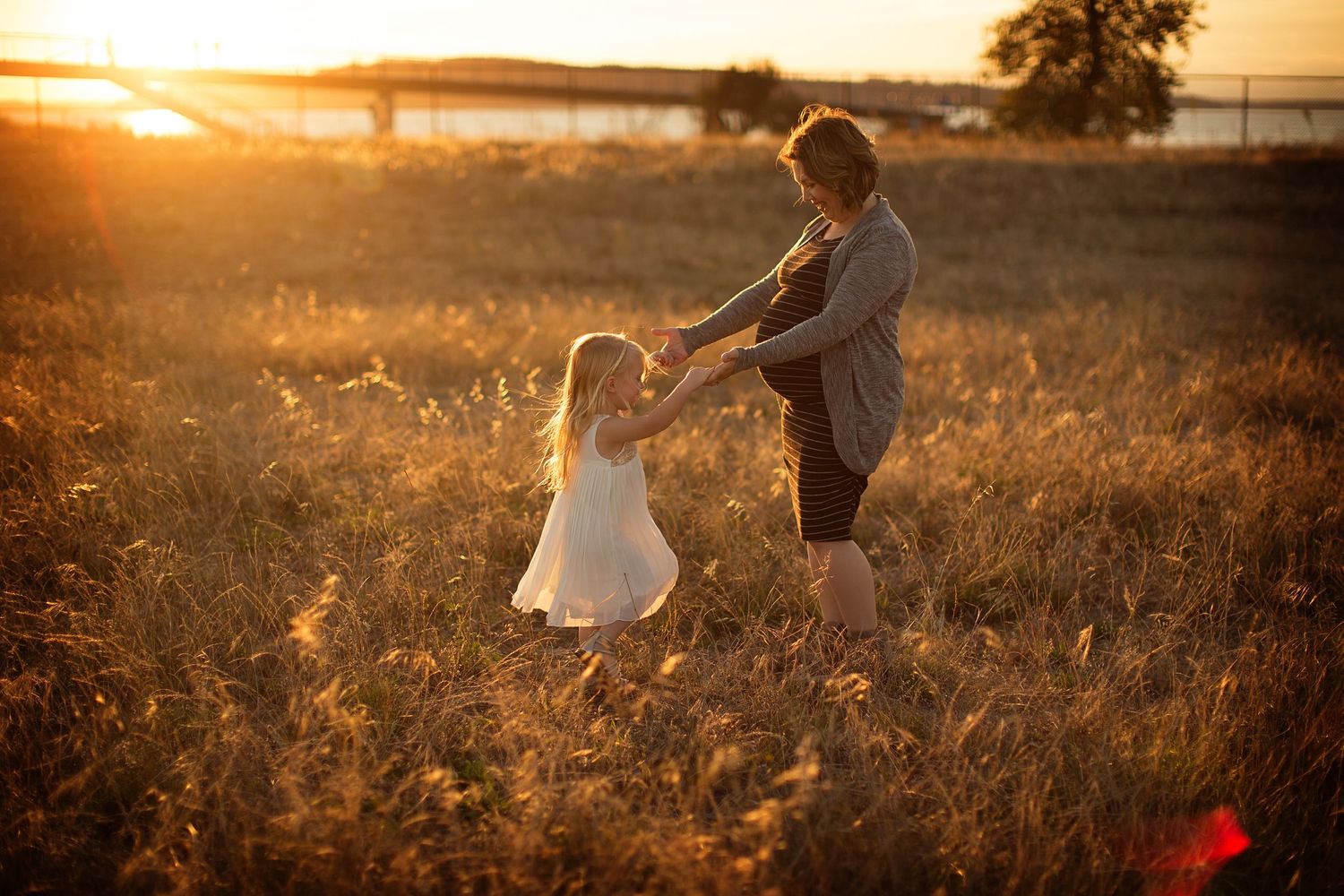 Golden sunset light illuminates a couple in a serene field during magic hour.