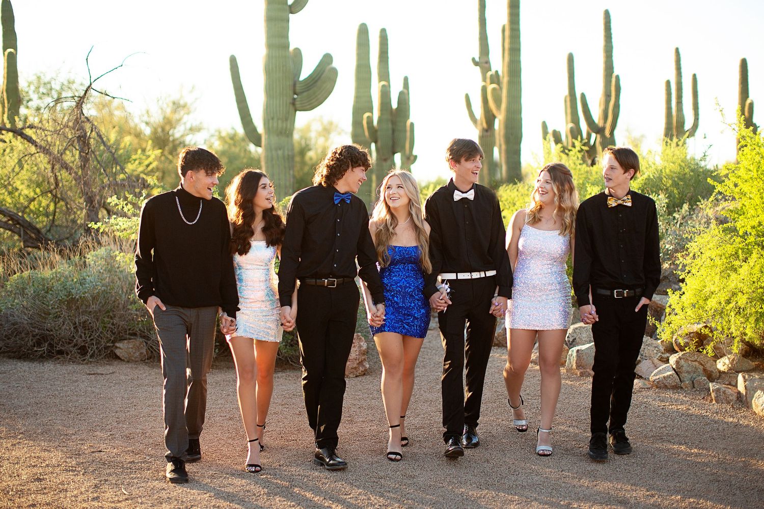 Group walking together through desert landscape with tall saguaro cacti.