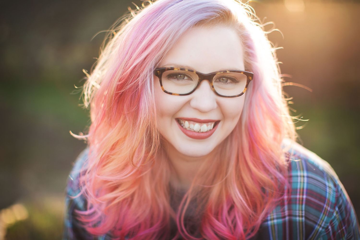 Portrait series with pink hair and glasses against warm sunset lighting.