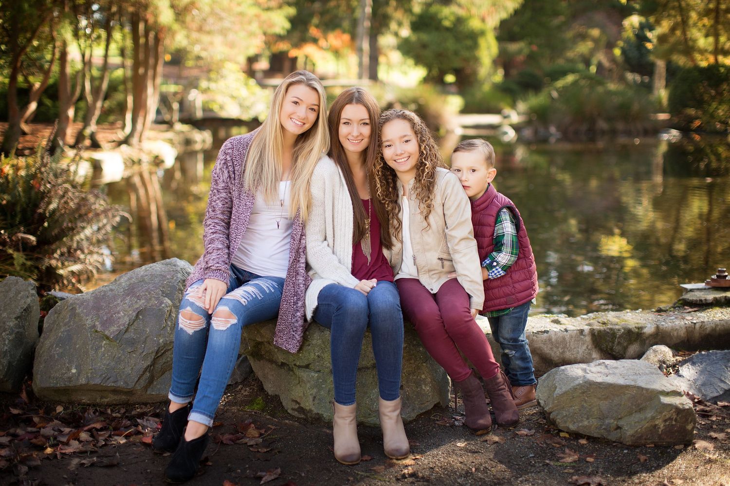 Candid family portraits taken by a pond with natural autumn scenery.