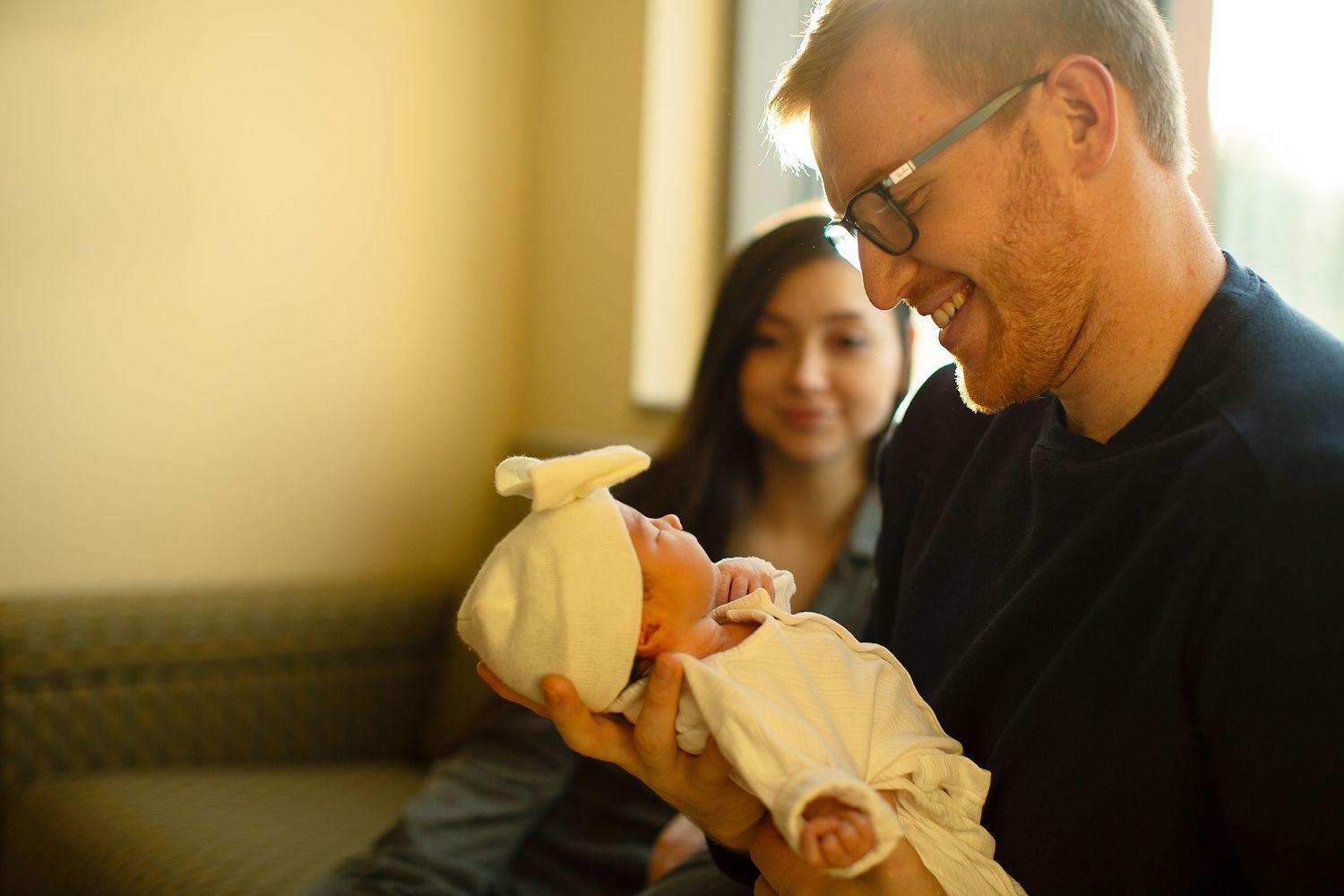 A warm-toned indoor portrait of family members sharing an intimate moment.