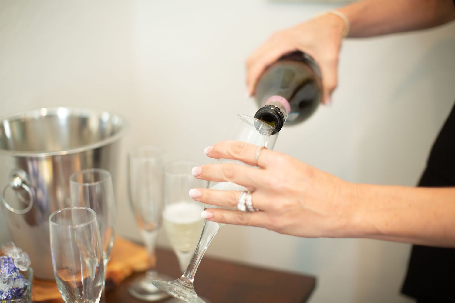 Hands pouring champagne into glasses during wedding day celebrations.