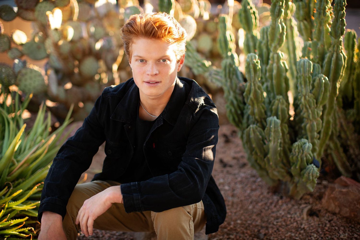 Outdoor portrait session among desert plants with dramatic lighting.