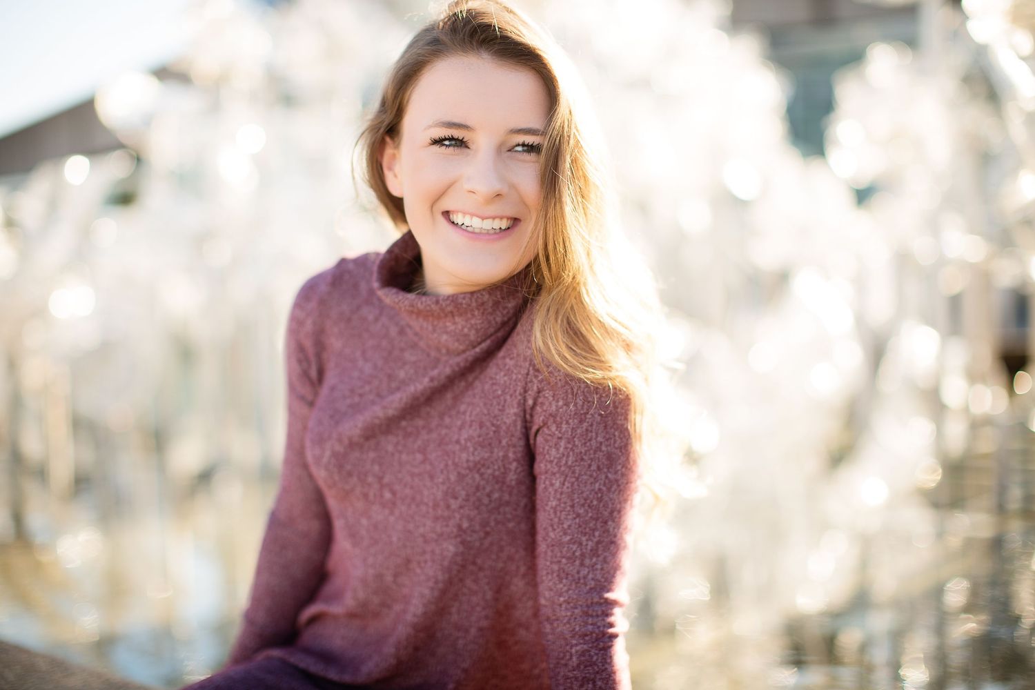 Woman in burgundy sweater smiles during winter photoshoot.