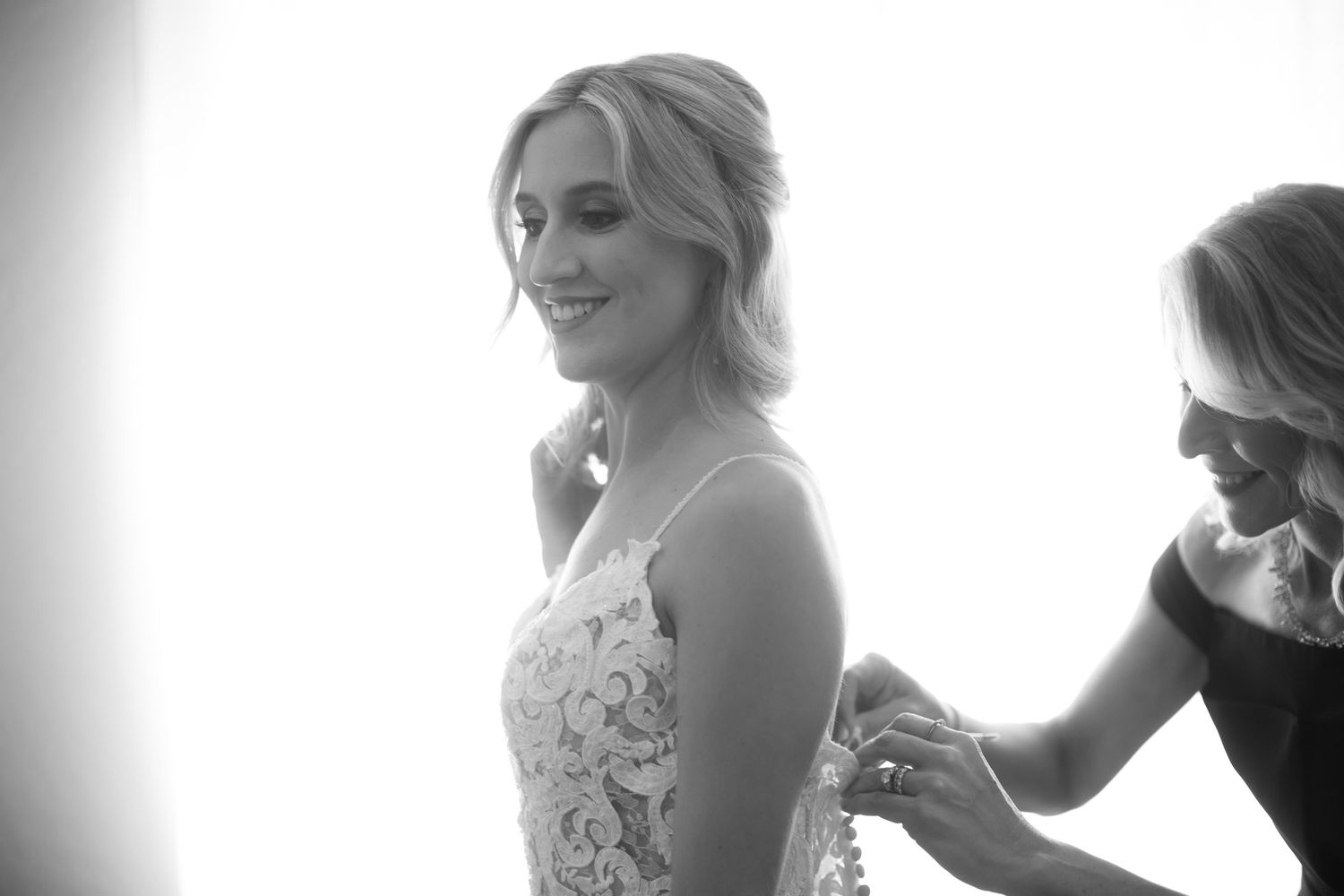 Wedding preparations in soft natural light as attendants help with final touches.
