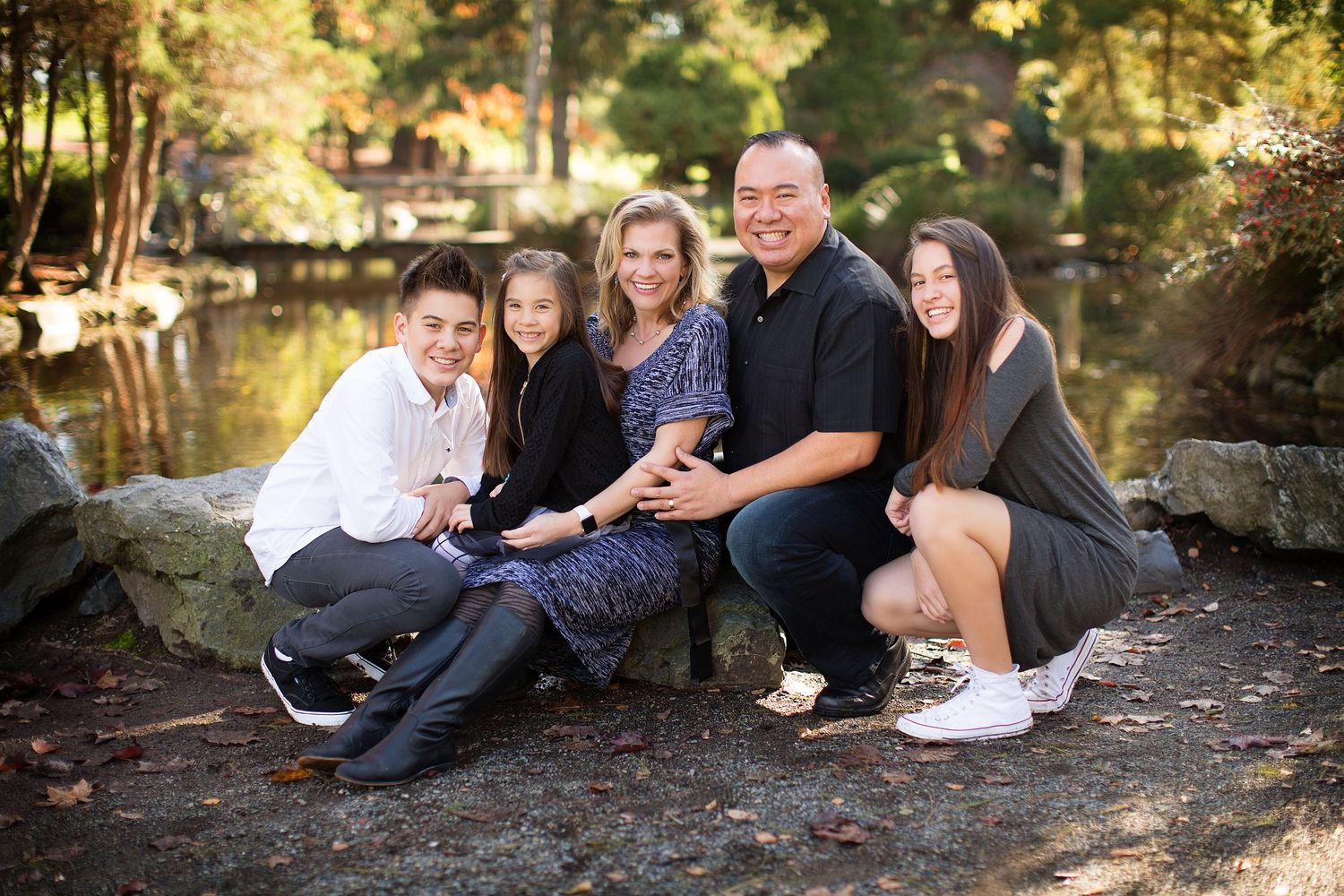 Family photo session on a wooded path with natural stone elements.