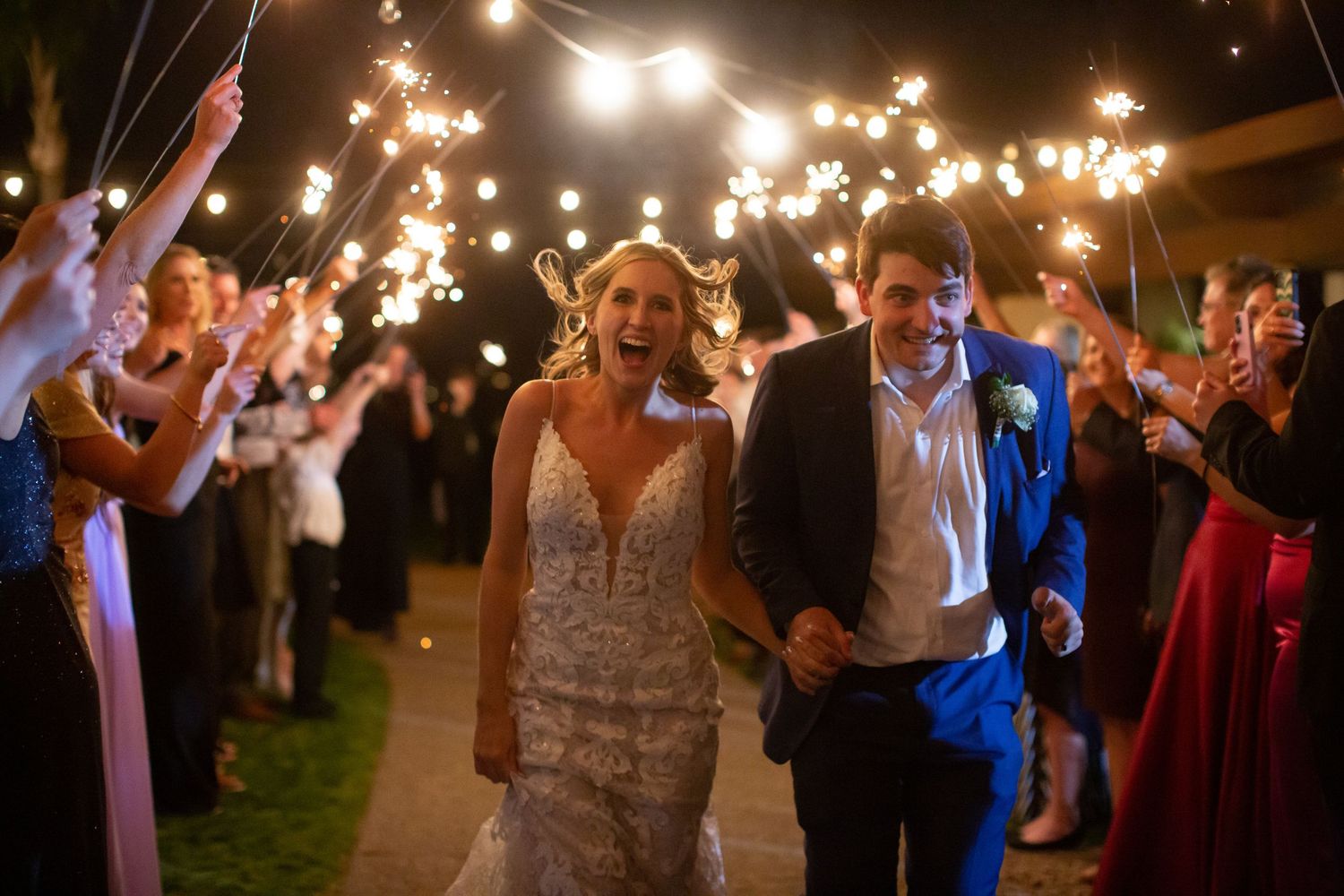 Evening wedding reception with guests dancing under string lights outdoors.