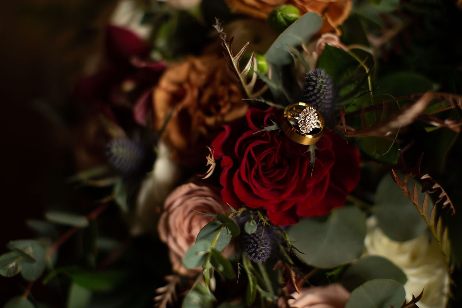 Rich autumn-colored wedding bouquet featuring deep red roses and mixed seasonal flowers.