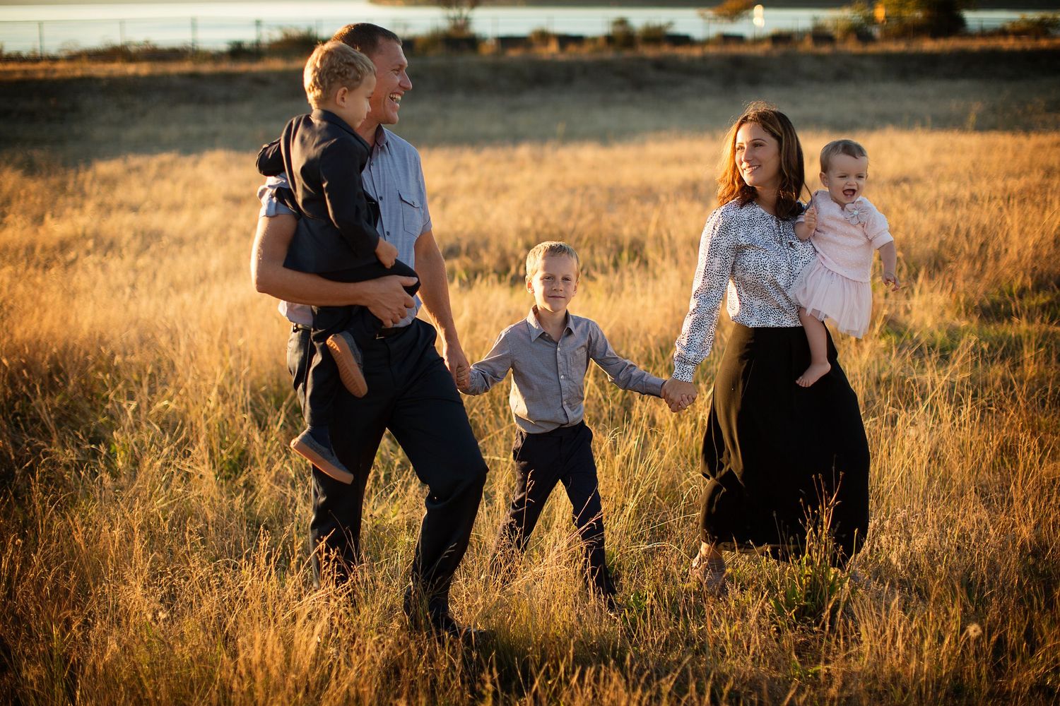Family enjoying golden hour photography session in a sun-lit field at sunset.