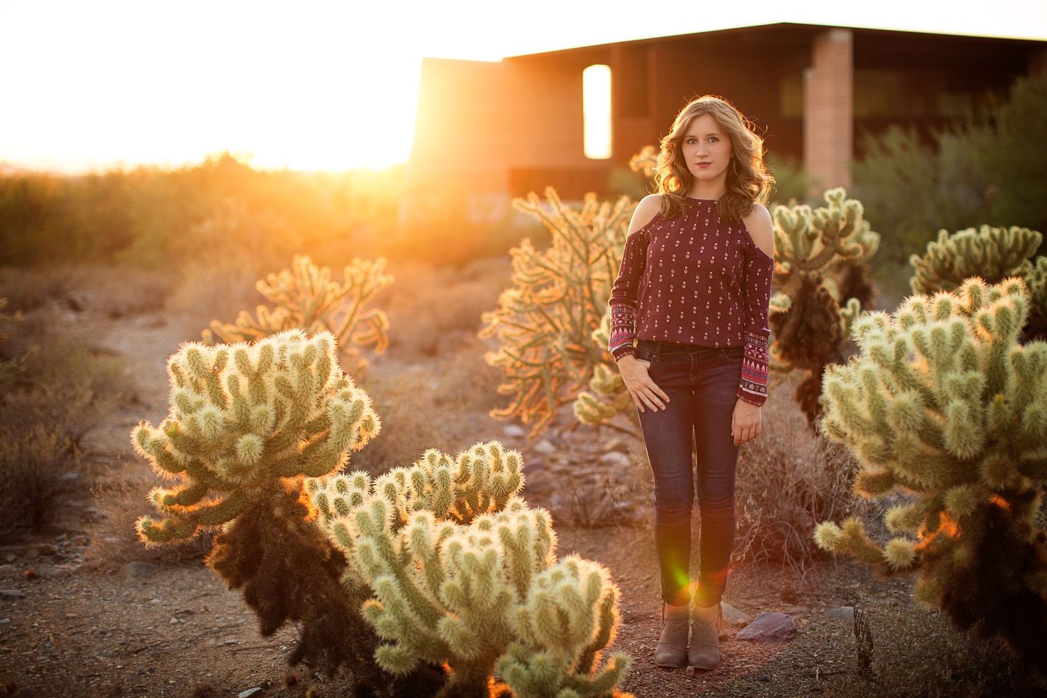 Desert sunset portrait session among blooming cacti with golden backlight.