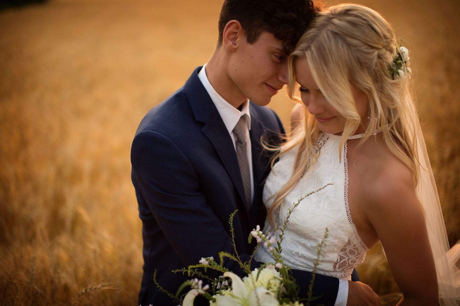 Romantic wedding portraits taken in a golden wheat field at sunset.