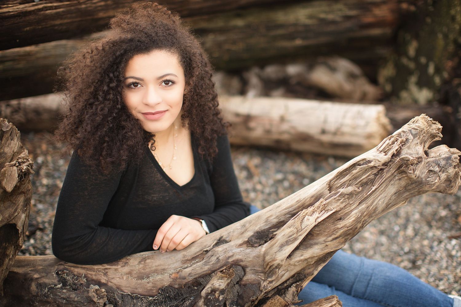 Portrait session with natural lighting and driftwood elements on a rocky beach.
