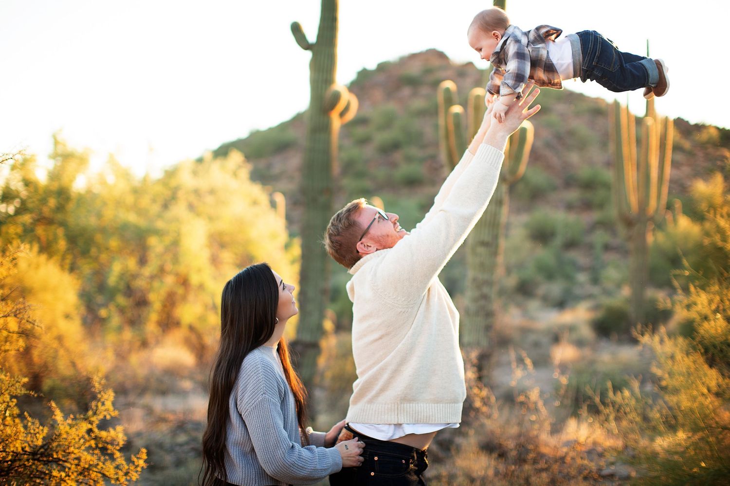 People playfully pose and interact in front of desert cacti during golden hour.