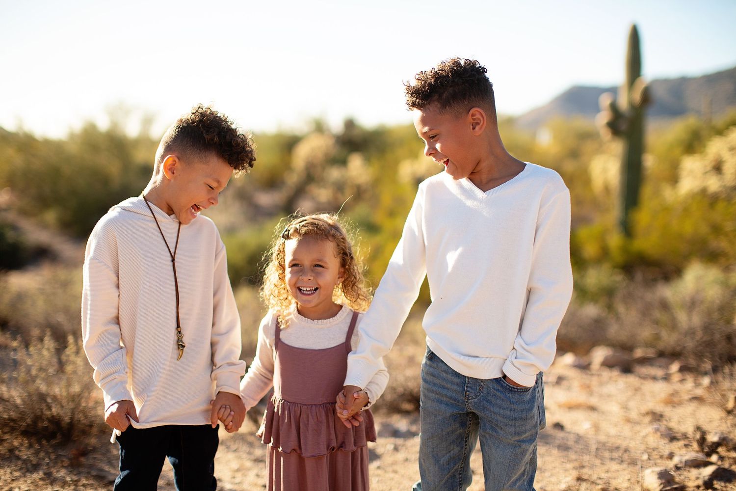 Family photo session in a desert landscape with cacti and mountains in the background.