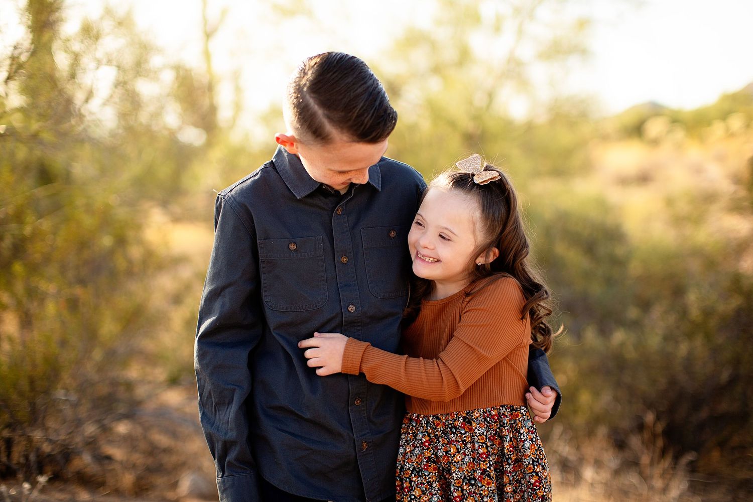 Couple embracing during a sunset photoshoot in a natural outdoor setting.
