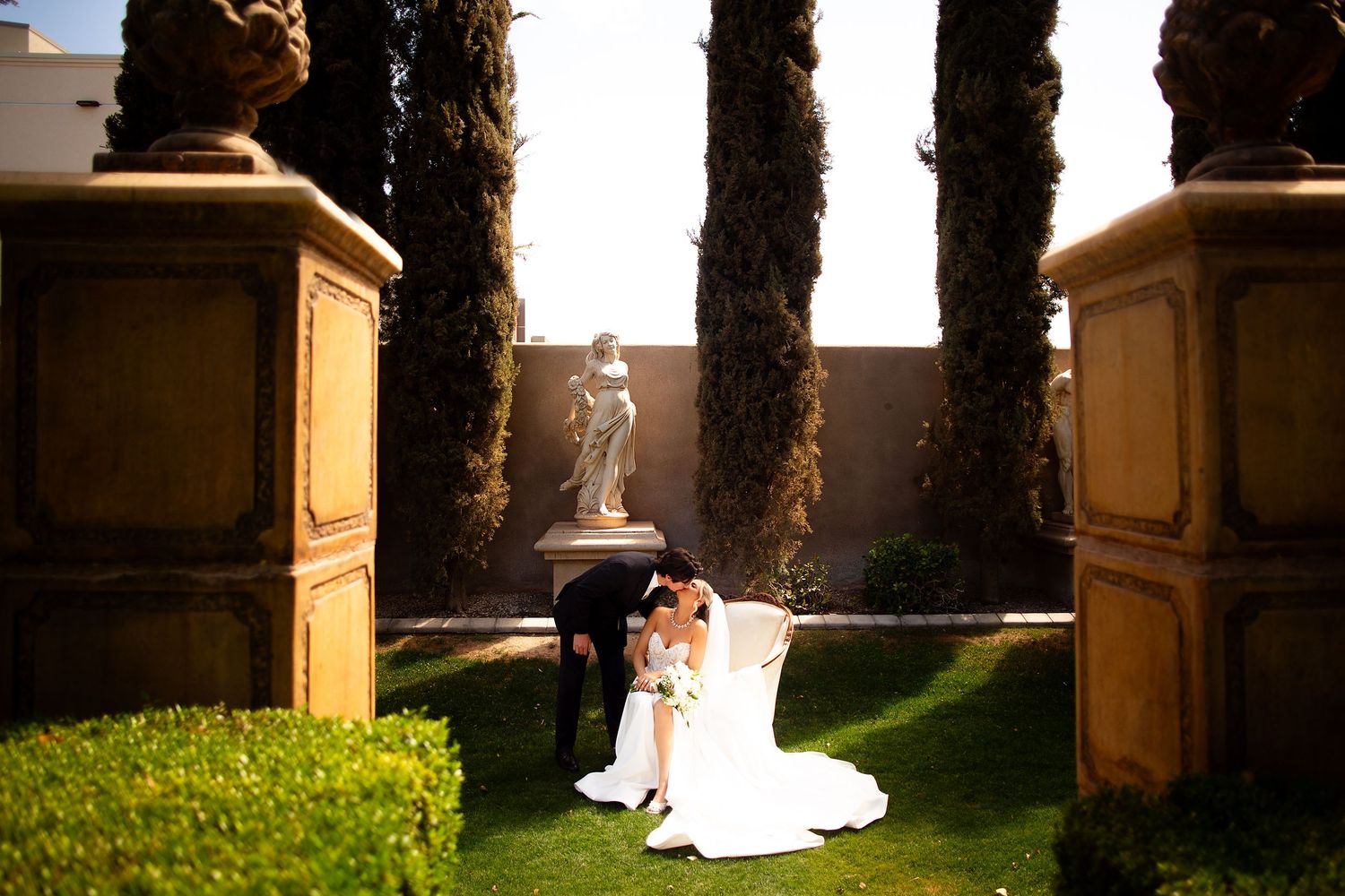 Architectural columns and cypress trees frame a scenic outdoor garden pathway.
