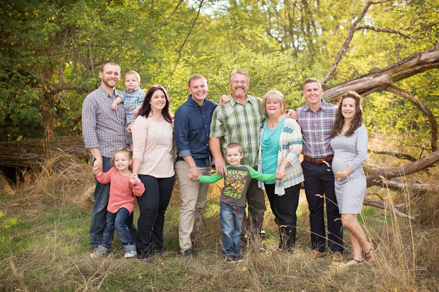 Extended family group photo taken outdoors in a wooded natural setting.