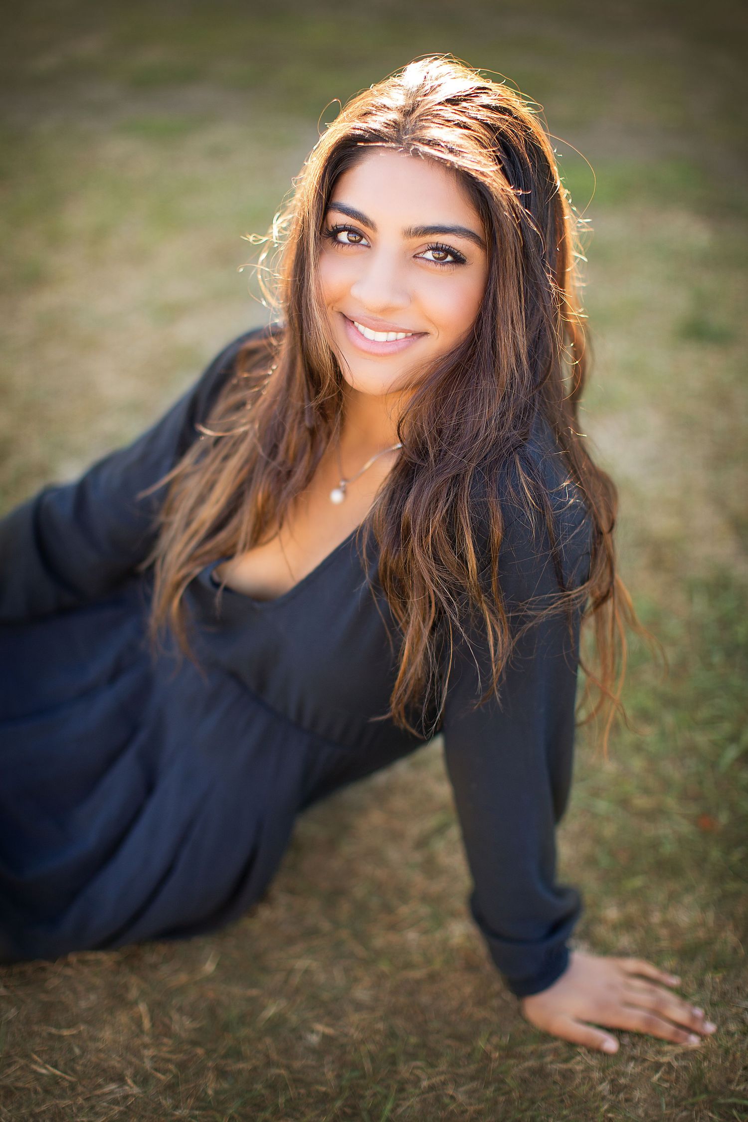 Outdoor portrait session featuring casual poses on grass with shallow depth of field.