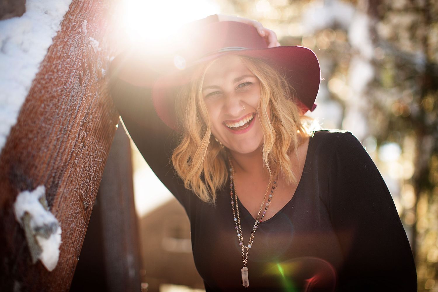 Portrait with sun flare through trees creating warm golden lighting.
