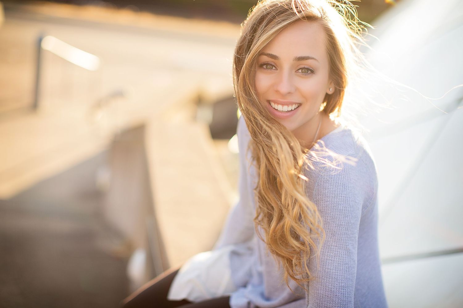 Woman in lavender sweater smiles in soft natural light.