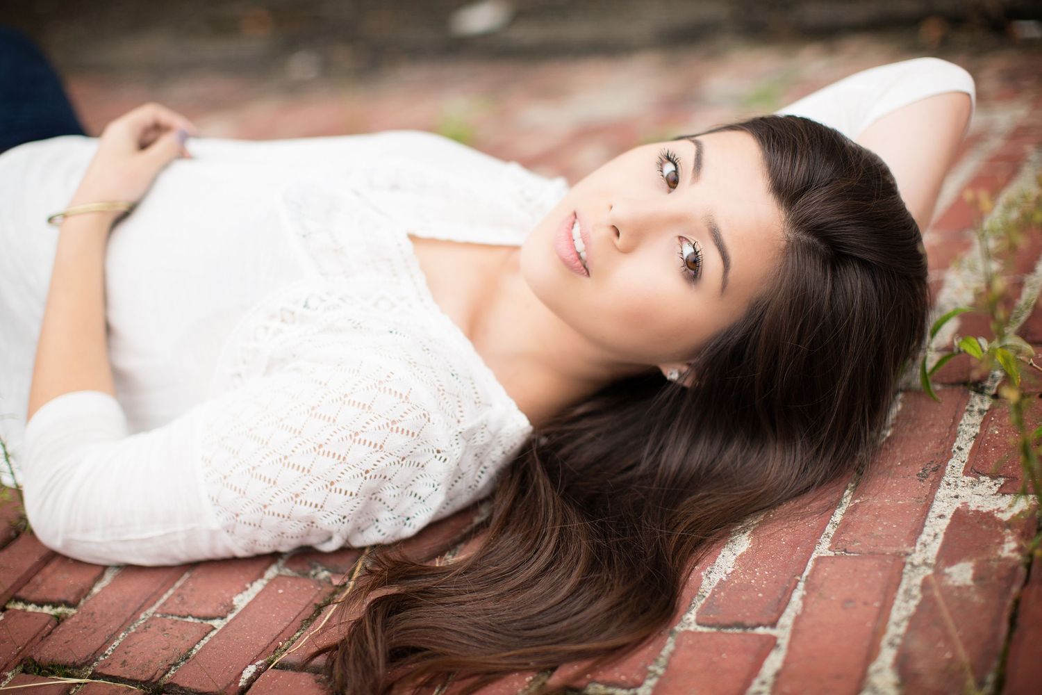 Elegant portrait series featuring a white lace dress against brick textures.