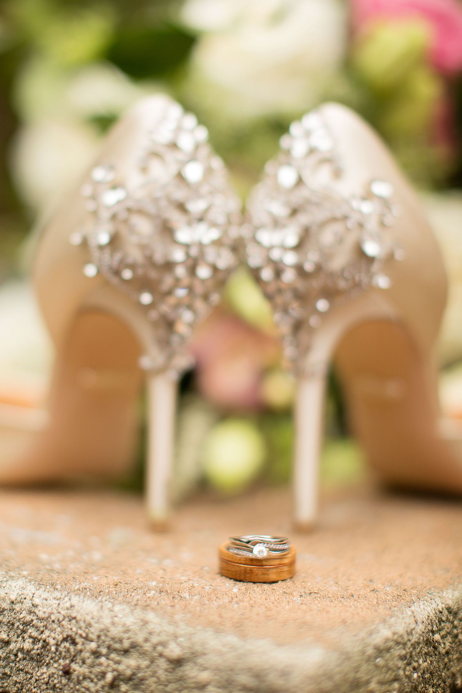 Wedding rings and crystal bridal shoes arranged for detail photo.