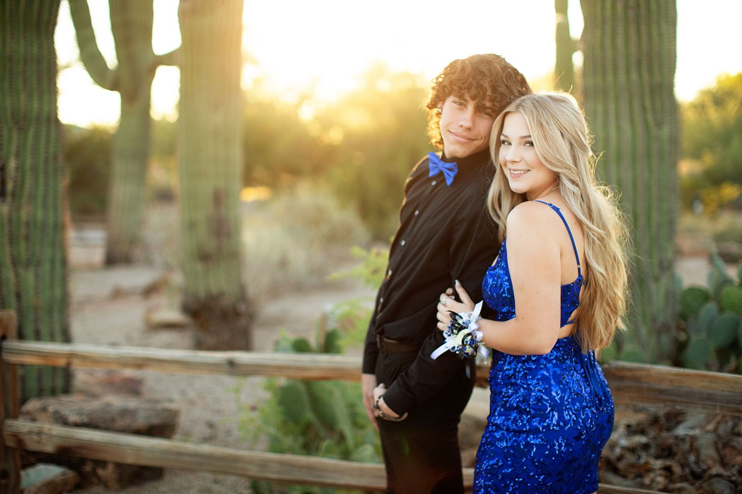 Romantic couple photoshoot with blue dress against desert cacti at sunset.