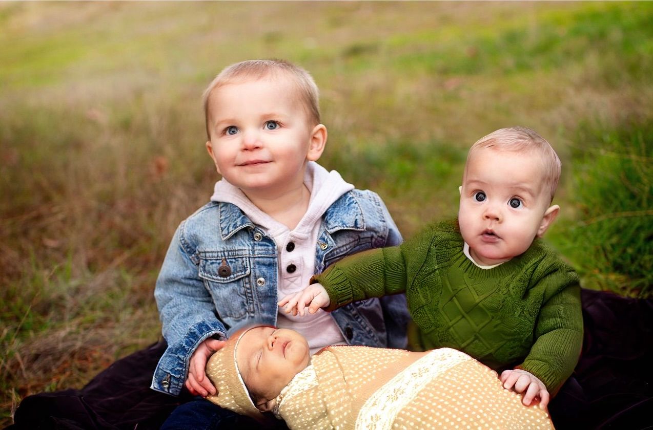 Young children playing together on grass during a family photo session.