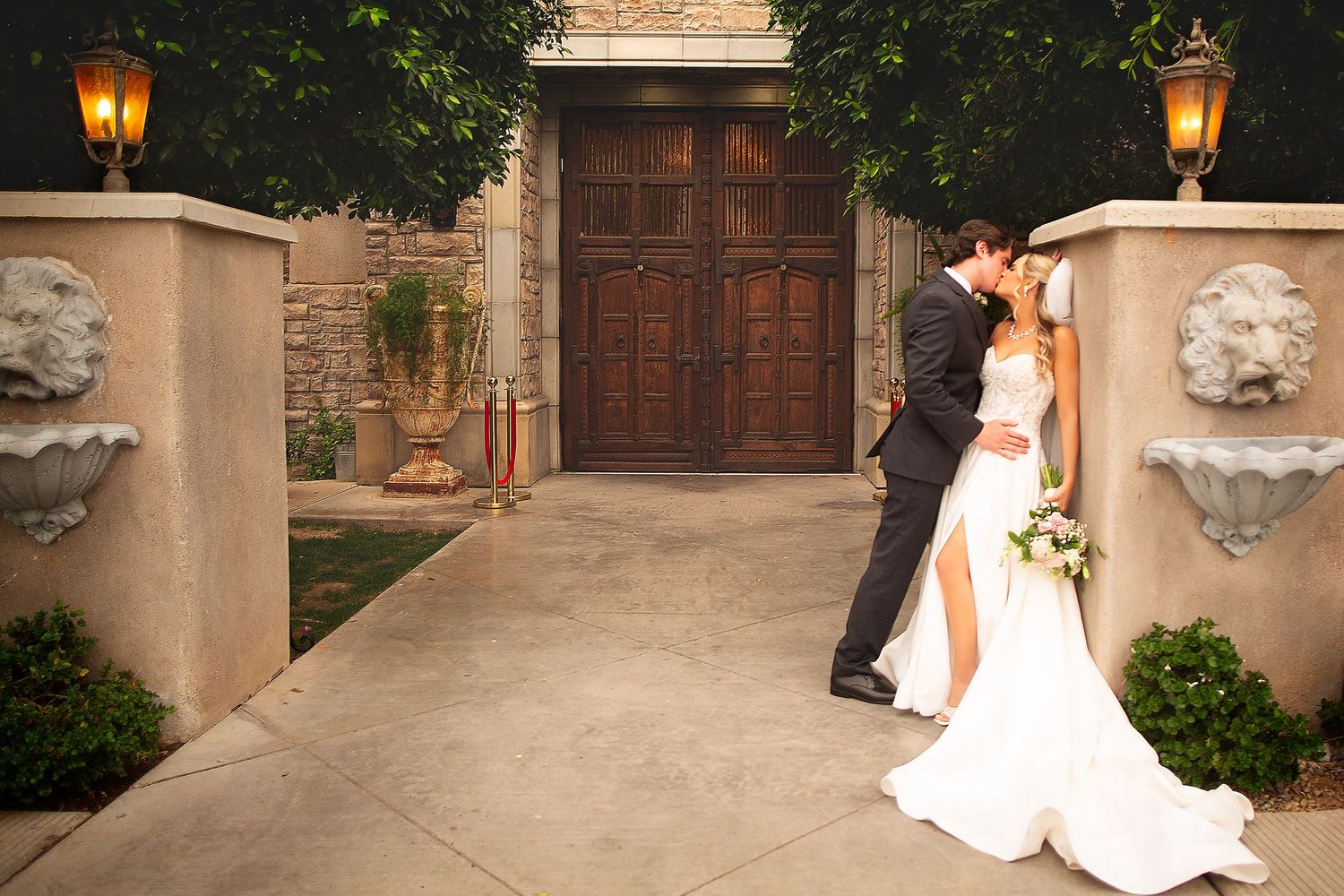 A couple poses together in front of a Mediterranean-style building with lanterns.