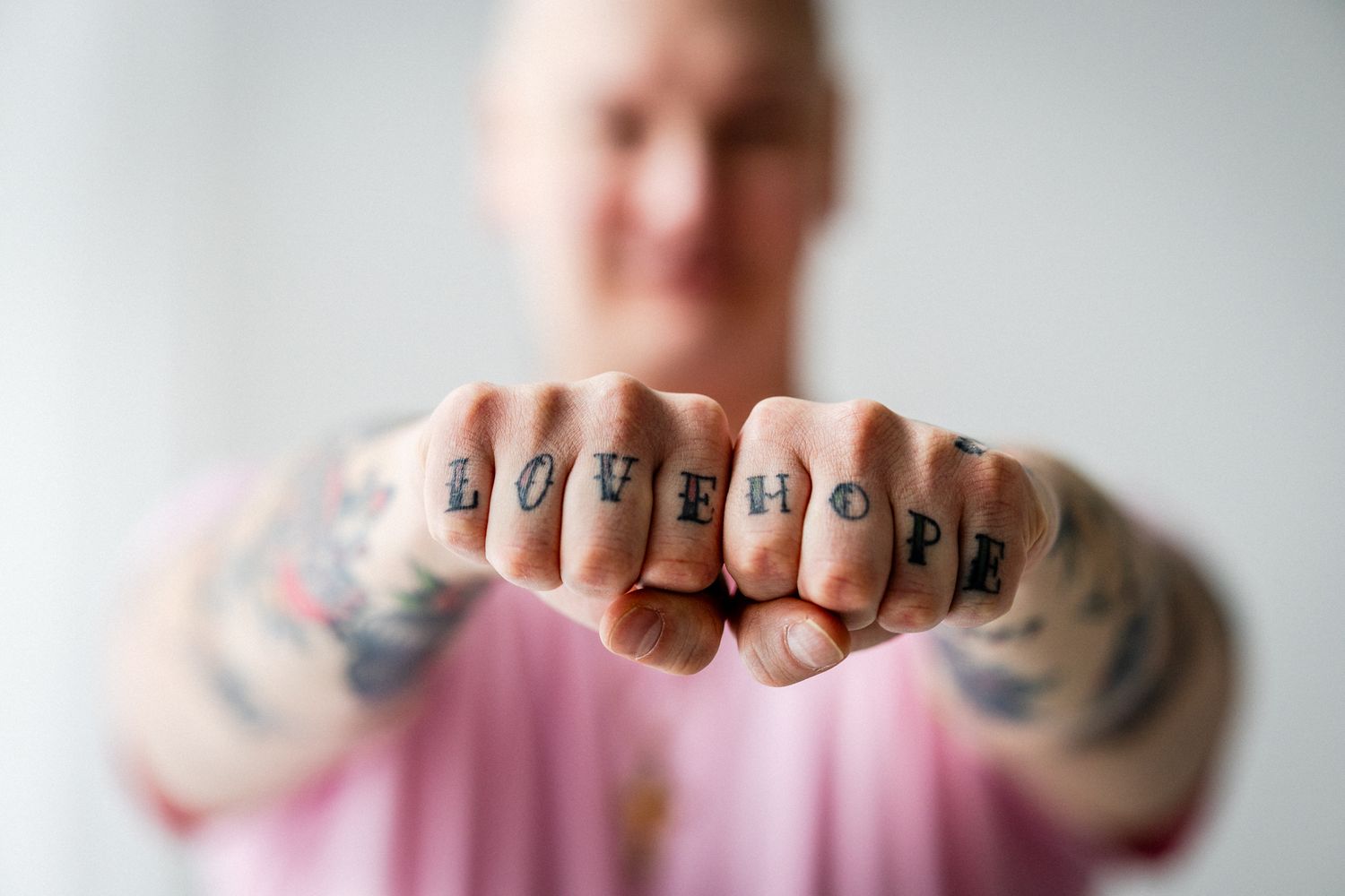 Yksityiskohtakuva miehen nyrkeistä. Rystysiin on tatuoitu sana 
