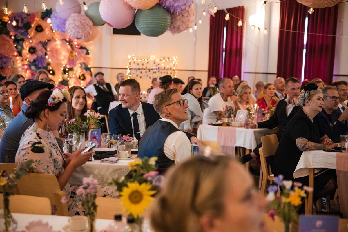 Koristeltu juhlasali täynnä juhlavieraita istumassa pöydän ääressä omilla paikoillaan.