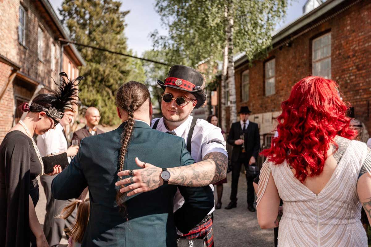 Hääpari ottaa vieraita vastaan Kellokosken Ruukin pihapiirissä. Vieraat on pukeutunut 20-luku teeman mukaisesti.