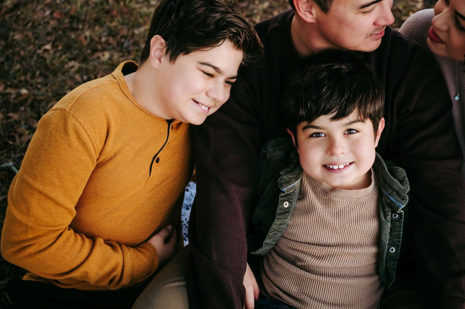 Candid moment of three friends laughing together while wearing cozy autumn sweaters.