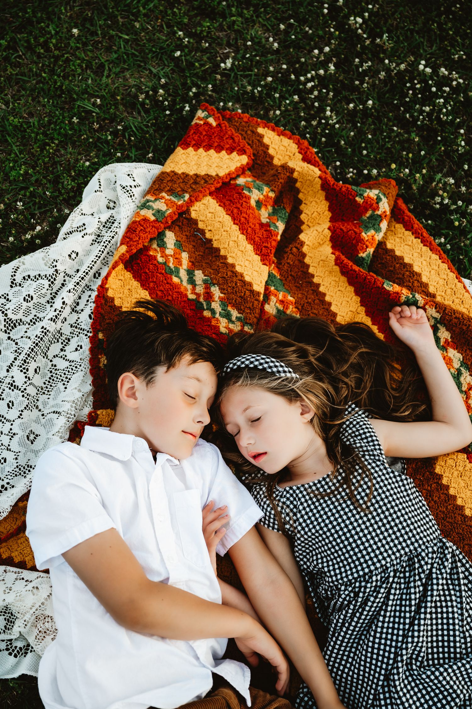 A couple in gingham and white clothing lying on autumn leaves in a romantic outdoor setting.
