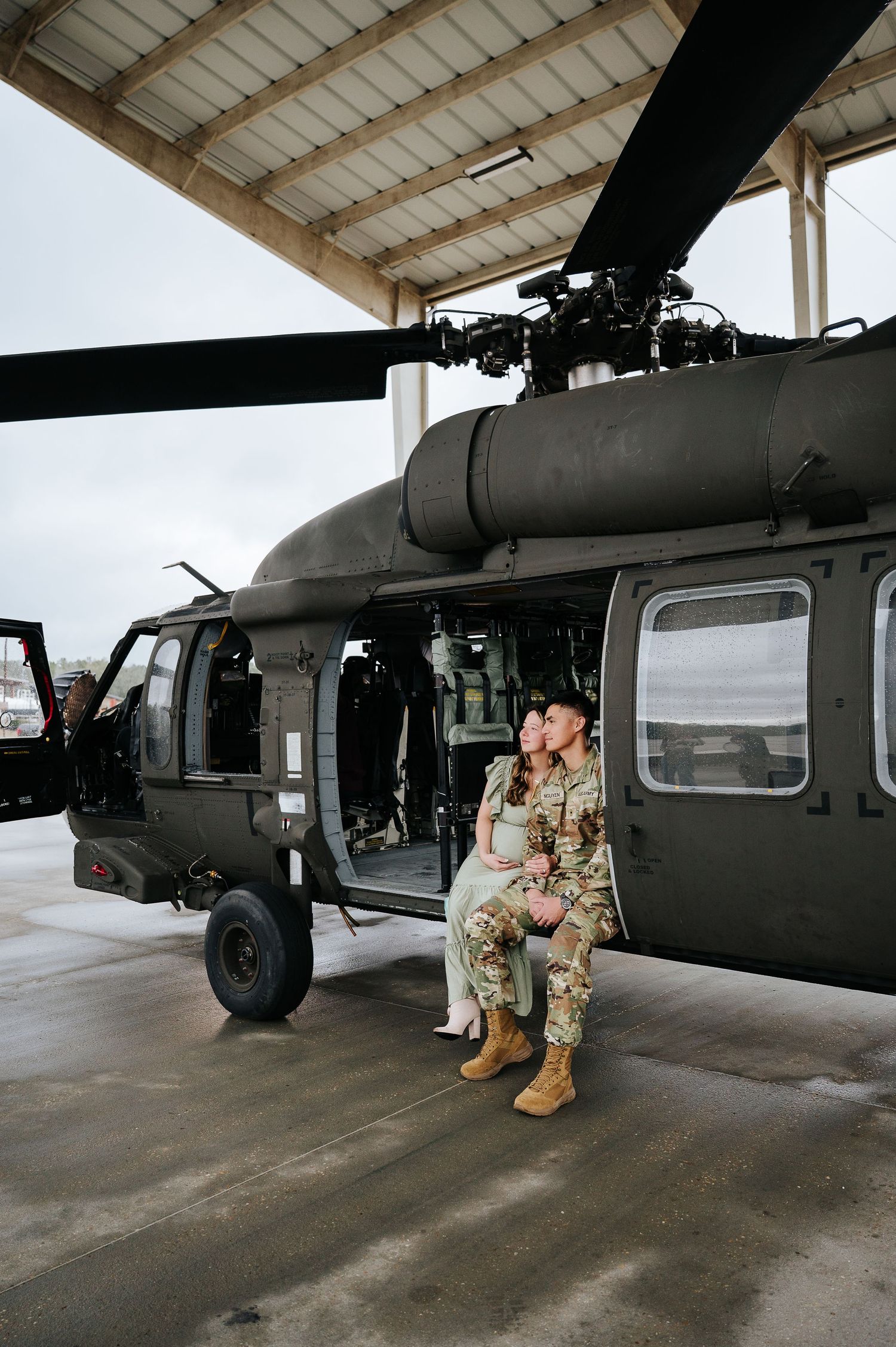 Military personnel inspect and perform maintenance checks on a Black Hawk helicopter in a hangar.