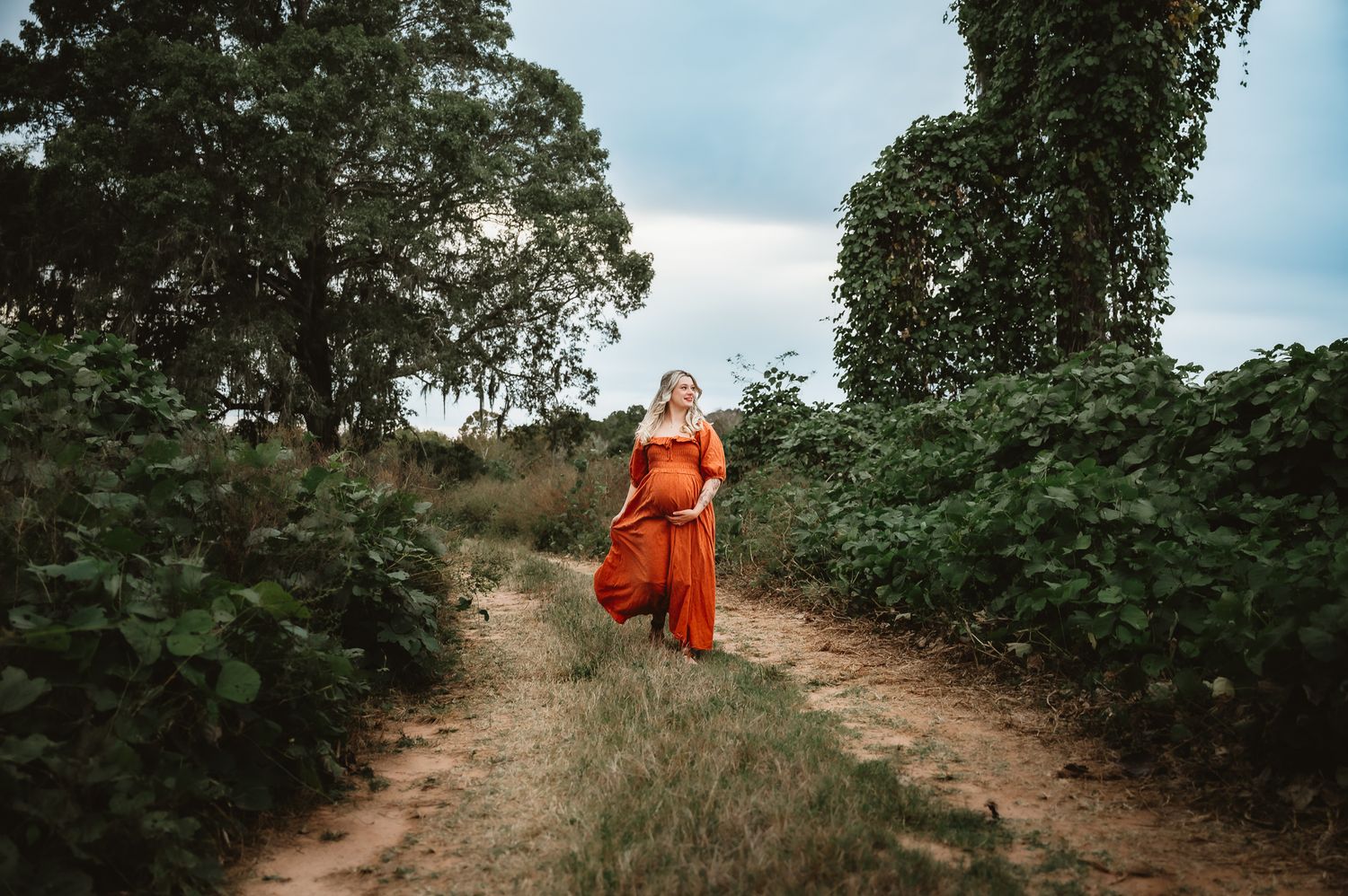 Buddhist monks walk along a dirt path through lush coffee plantations in the countryside.