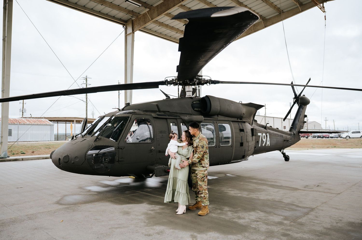 Military personnel prepare a UH-60 Black Hawk helicopter for maintenance operations on an airfield.
