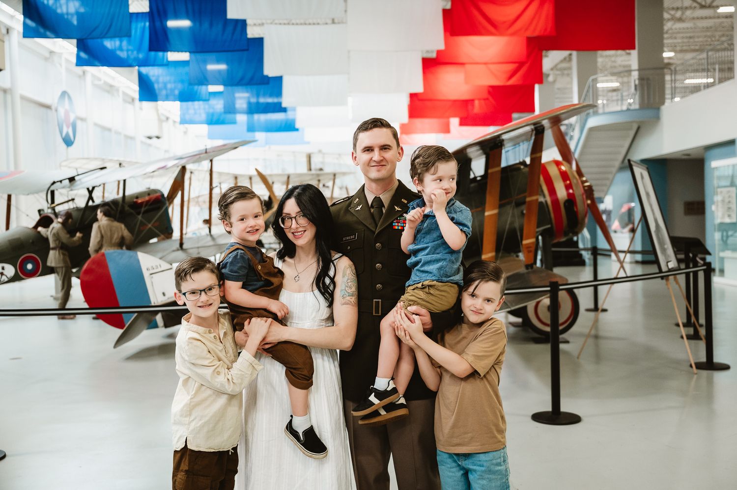 Aviation museum exhibit featuring vintage aircraft displays with red and blue banners overhead.