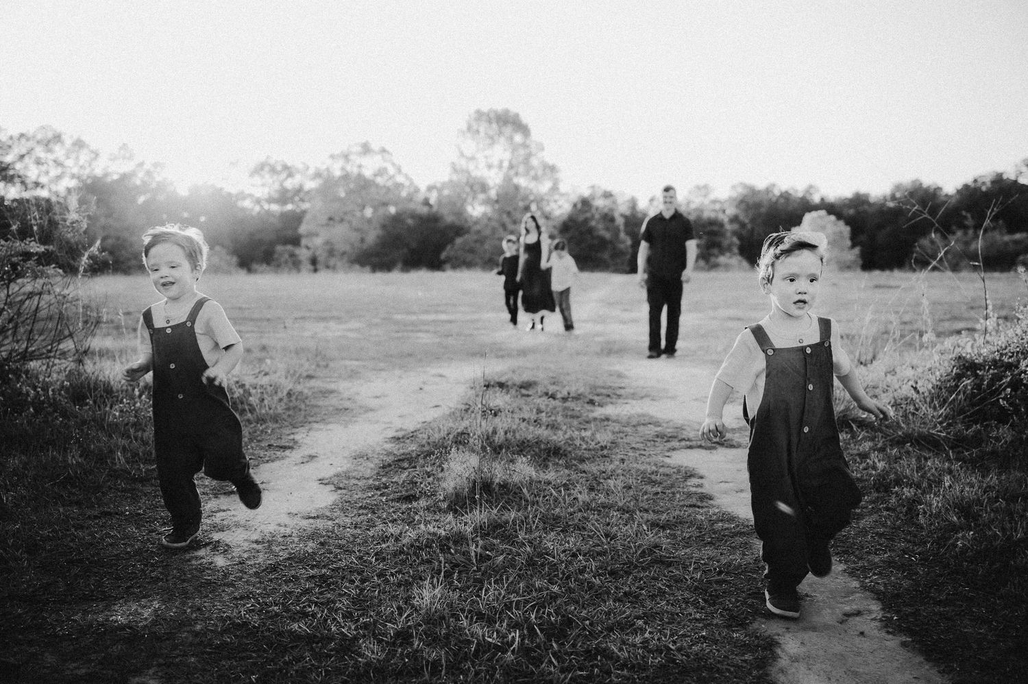 Black and white panoramic series of a family playing in an open field.