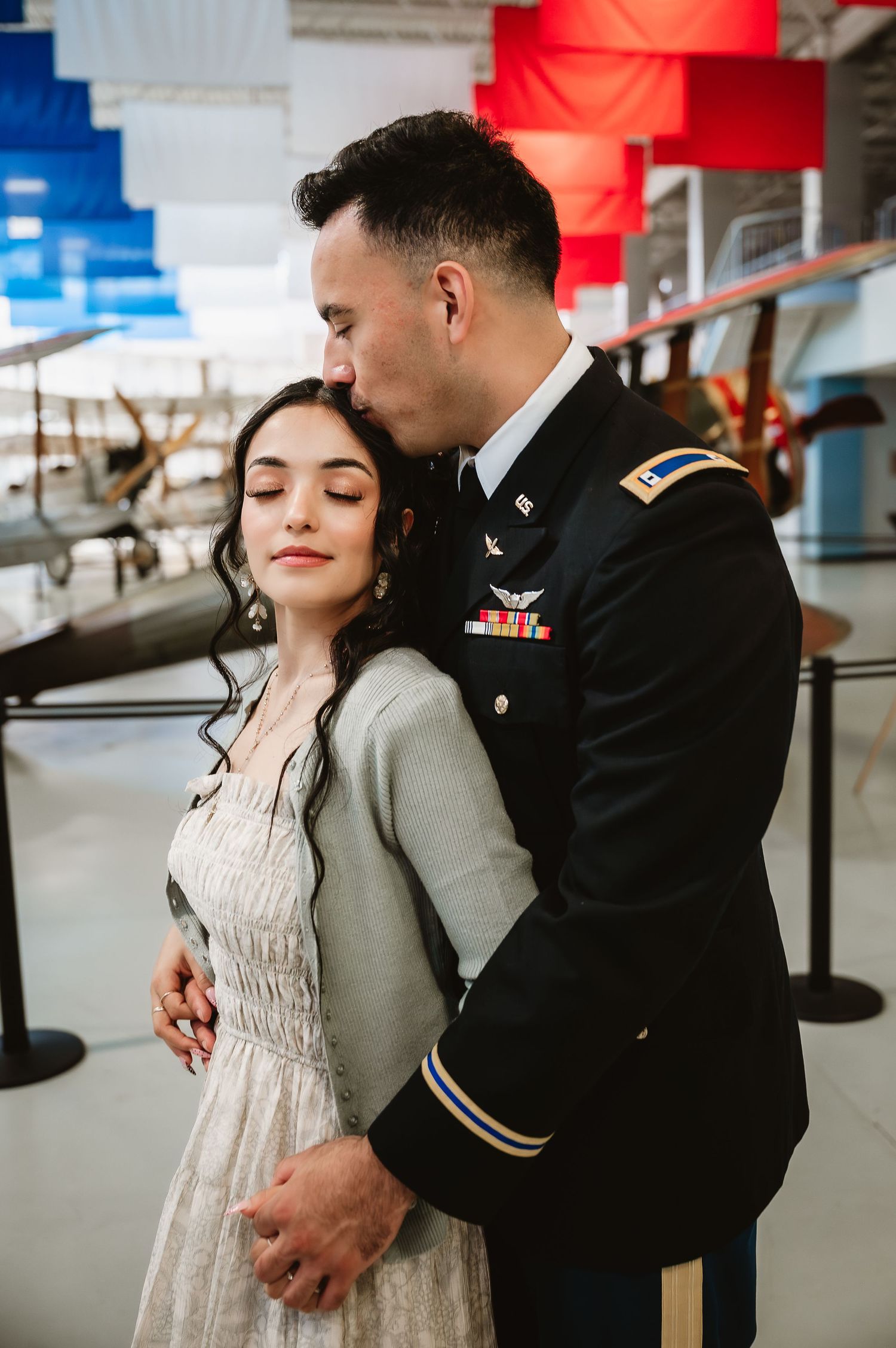 A romantic couple in formal attire share intimate moments in what appears to be an airport terminal setting.