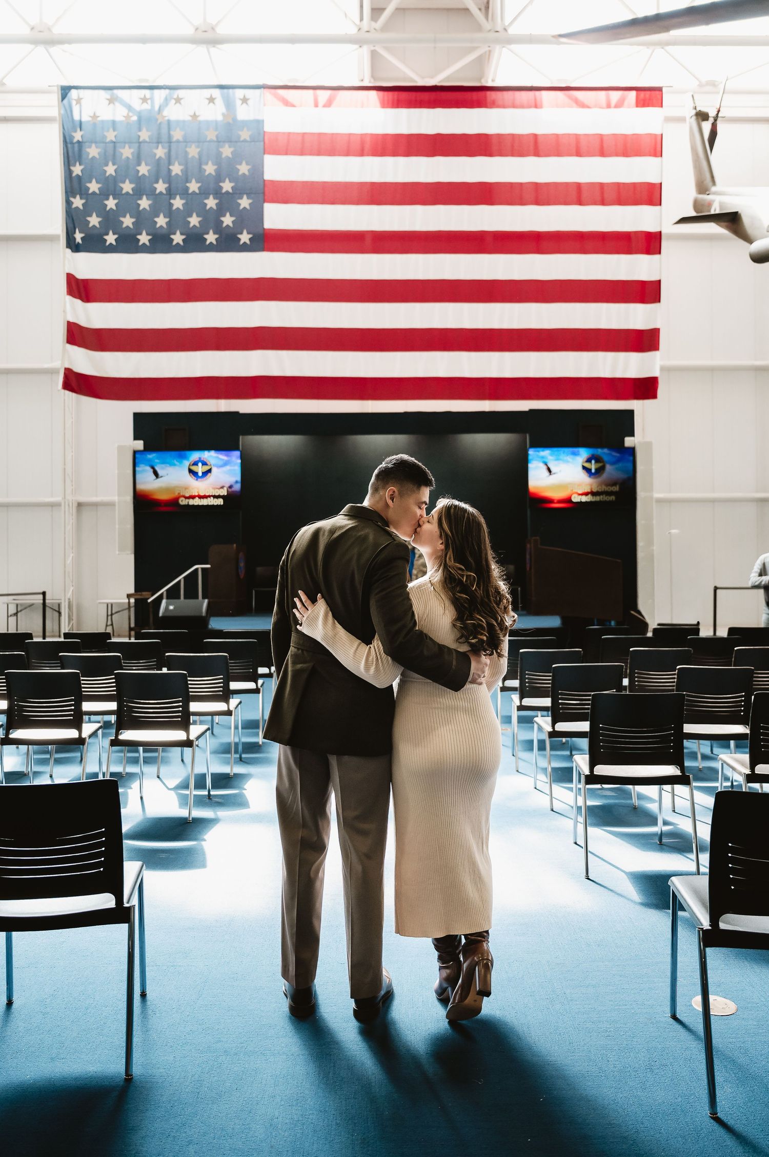 Four sequential photos of a couple embracing under American flags in an empty auditorium with blue lighting.