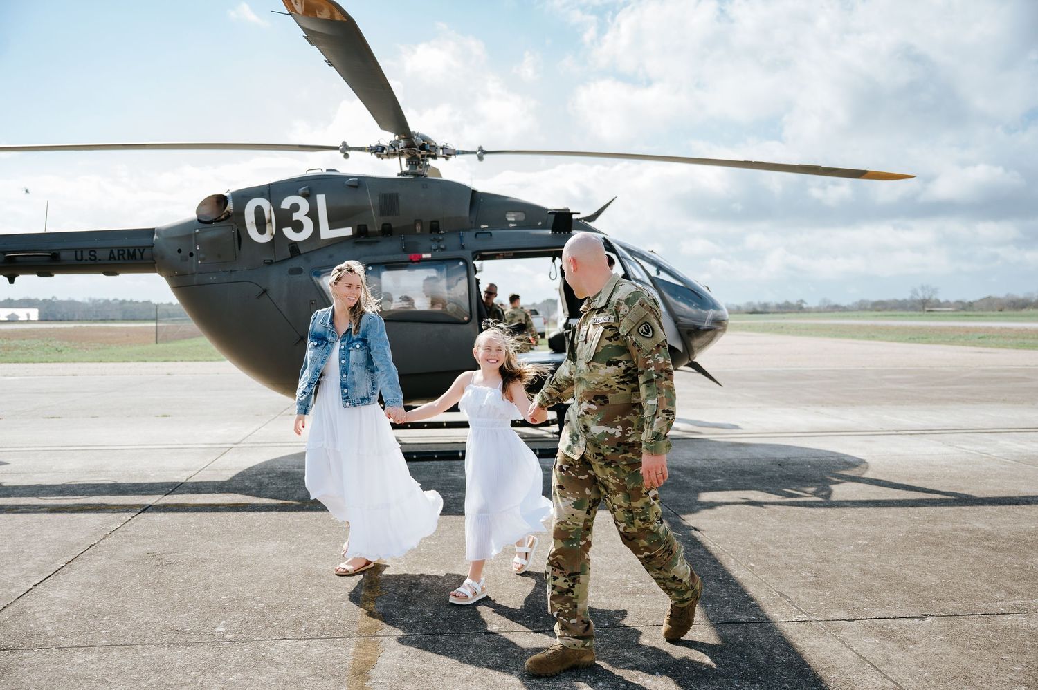Military personnel assist with boarding and unloading from a helicopter on an airfield tarmac during operations.