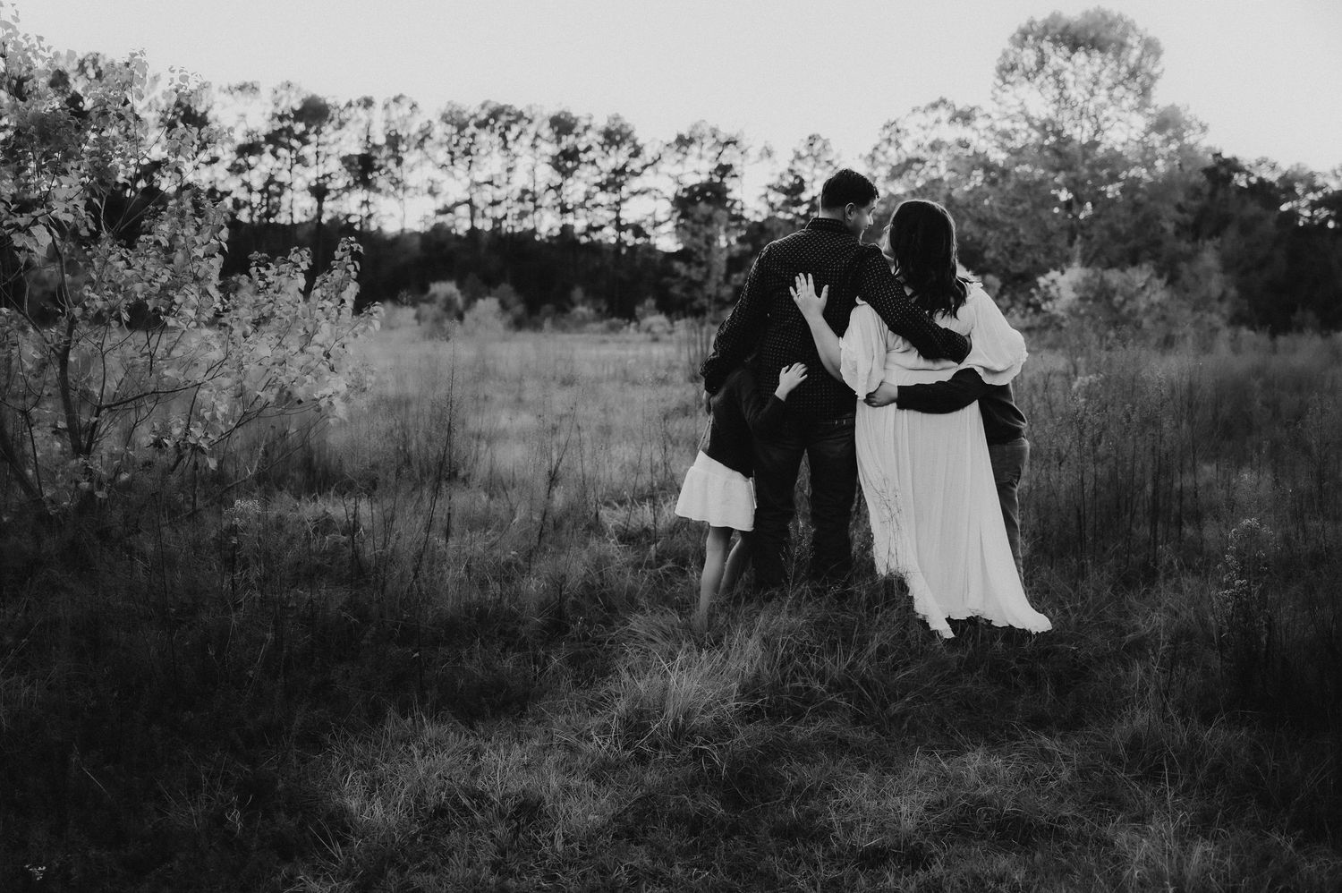 A black and white vintage wedding photo series showing a couple dancing and embracing in a grassy field.