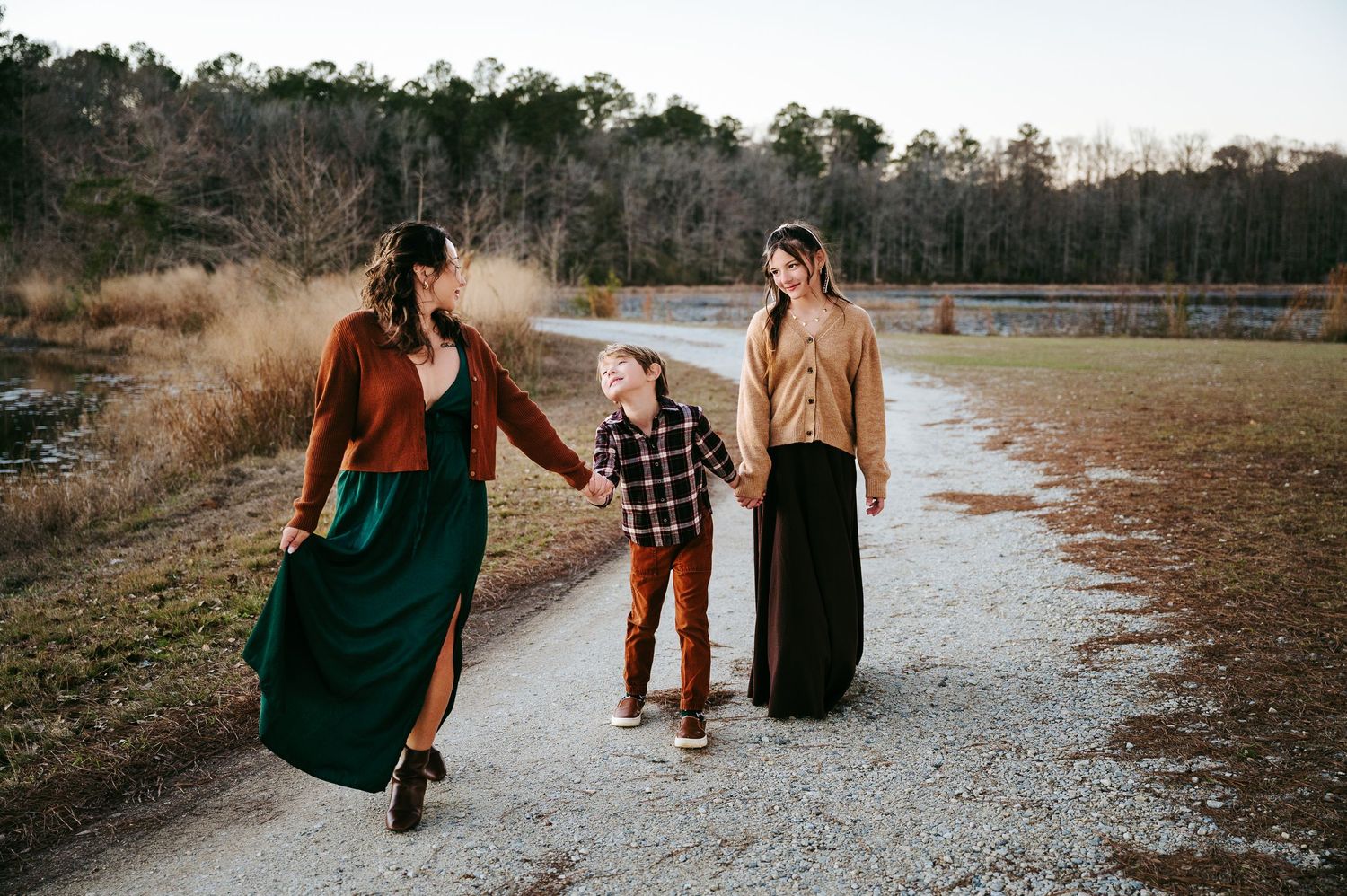 Group walking together on a gravel path through autumn foliage carrying luggage and bags.