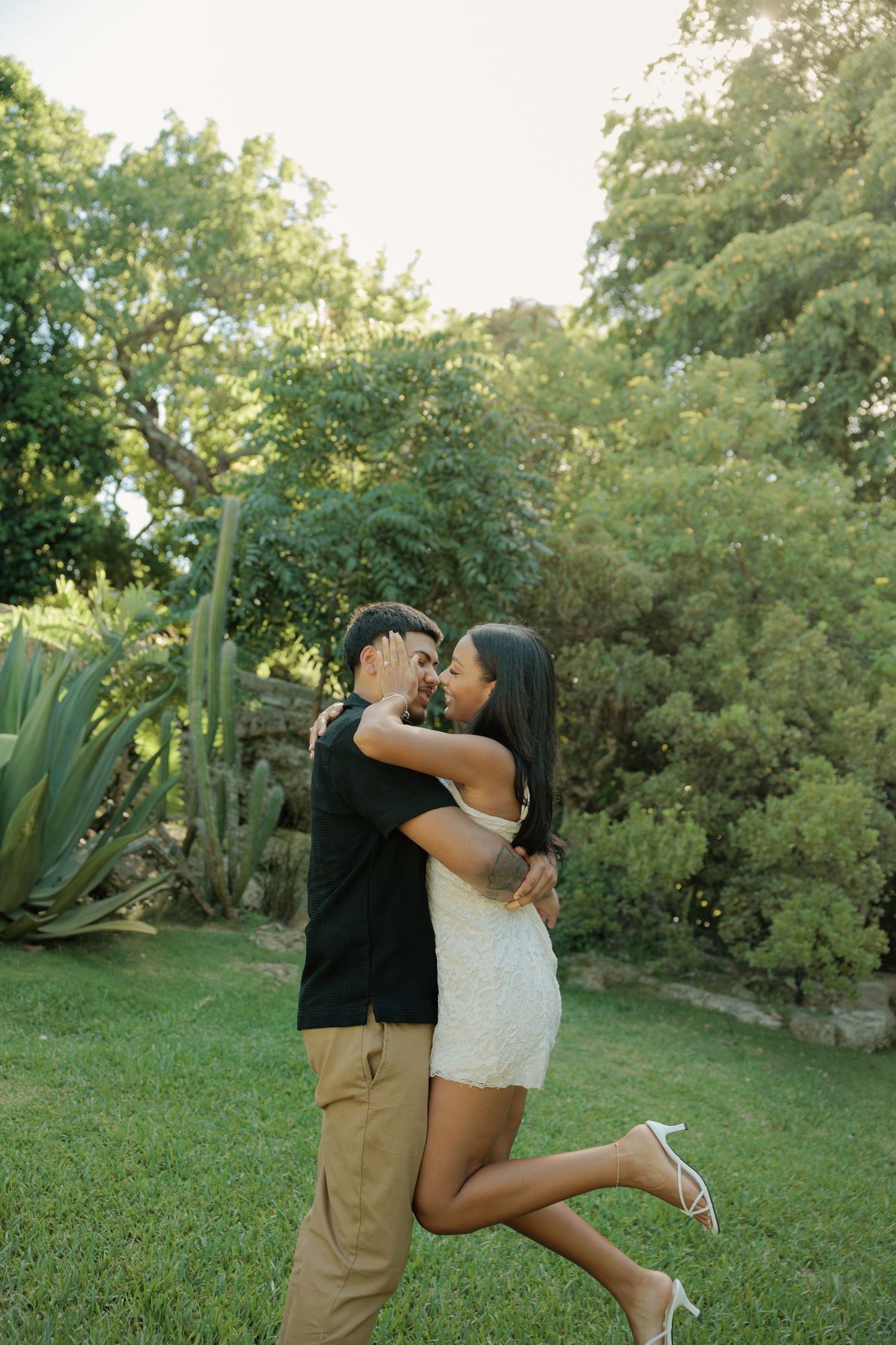 A romantic outdoor photo series shows a couple embracing in a lush garden setting on a sunny day.