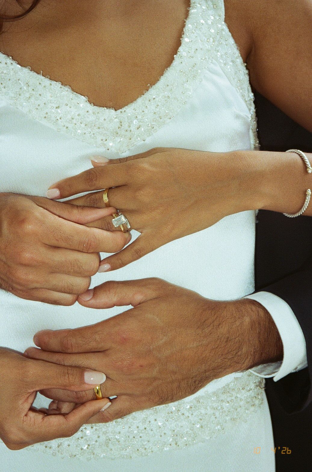 Bride and groom displaying wedding rings on their hands, with diamond engagement ring and gold bands.