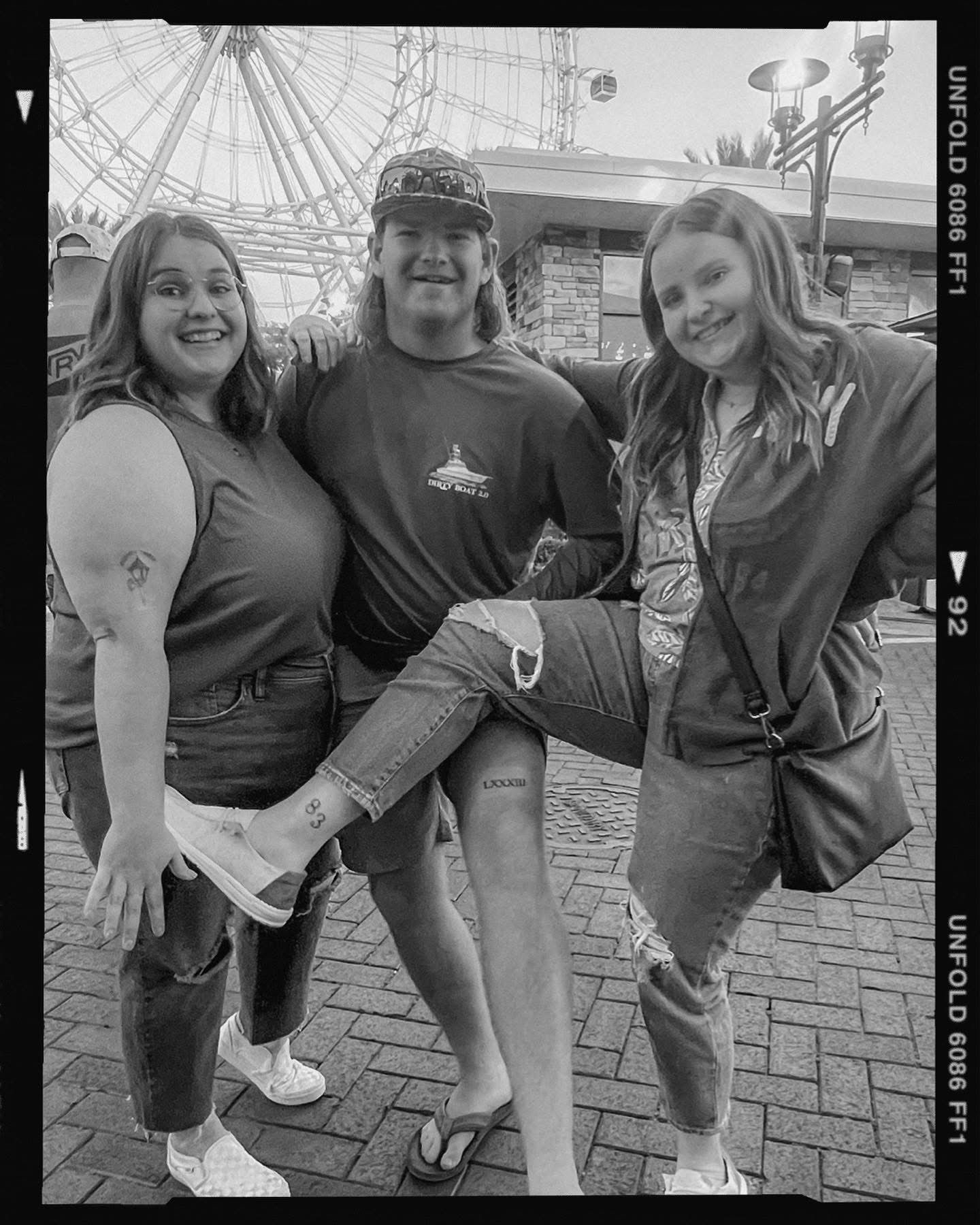 Group of people crouching down together and posing playfully on a brick paved surface.