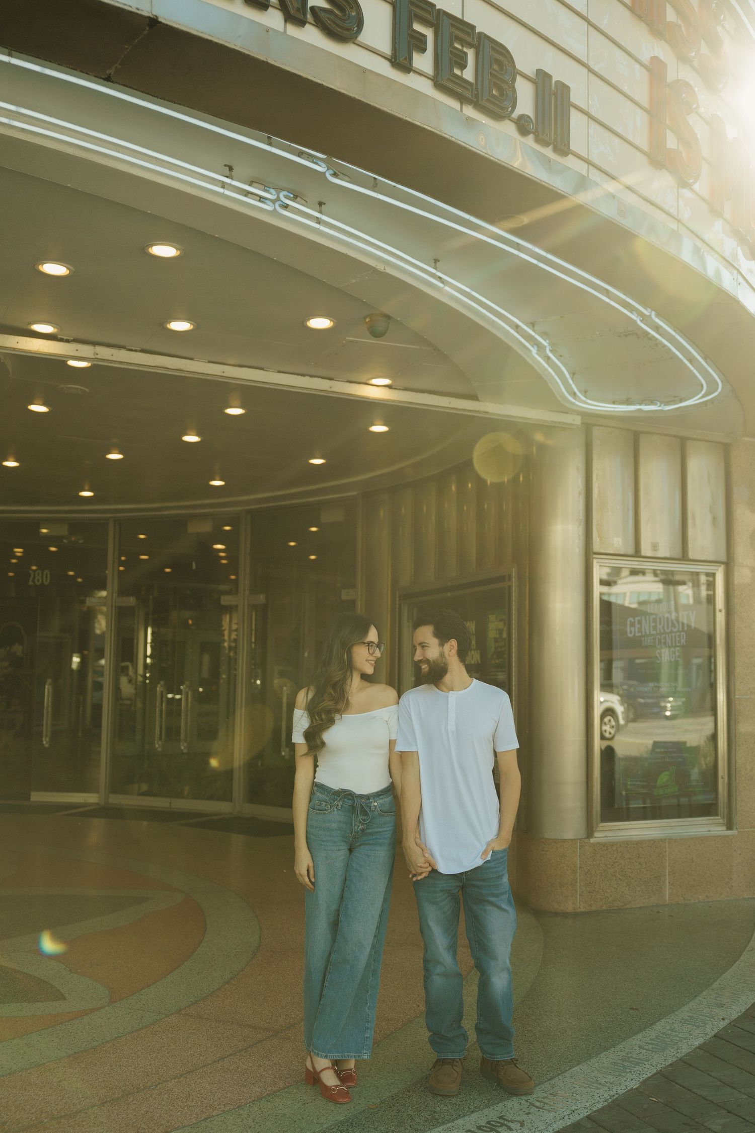 A couple walks together outside a building with curved glass windows and recessed lighting in a series of connected photos.